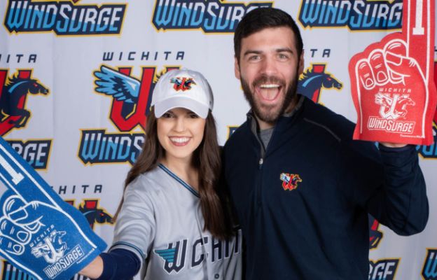couple posing with triple a baseball team wind surge gear in wichita kansas